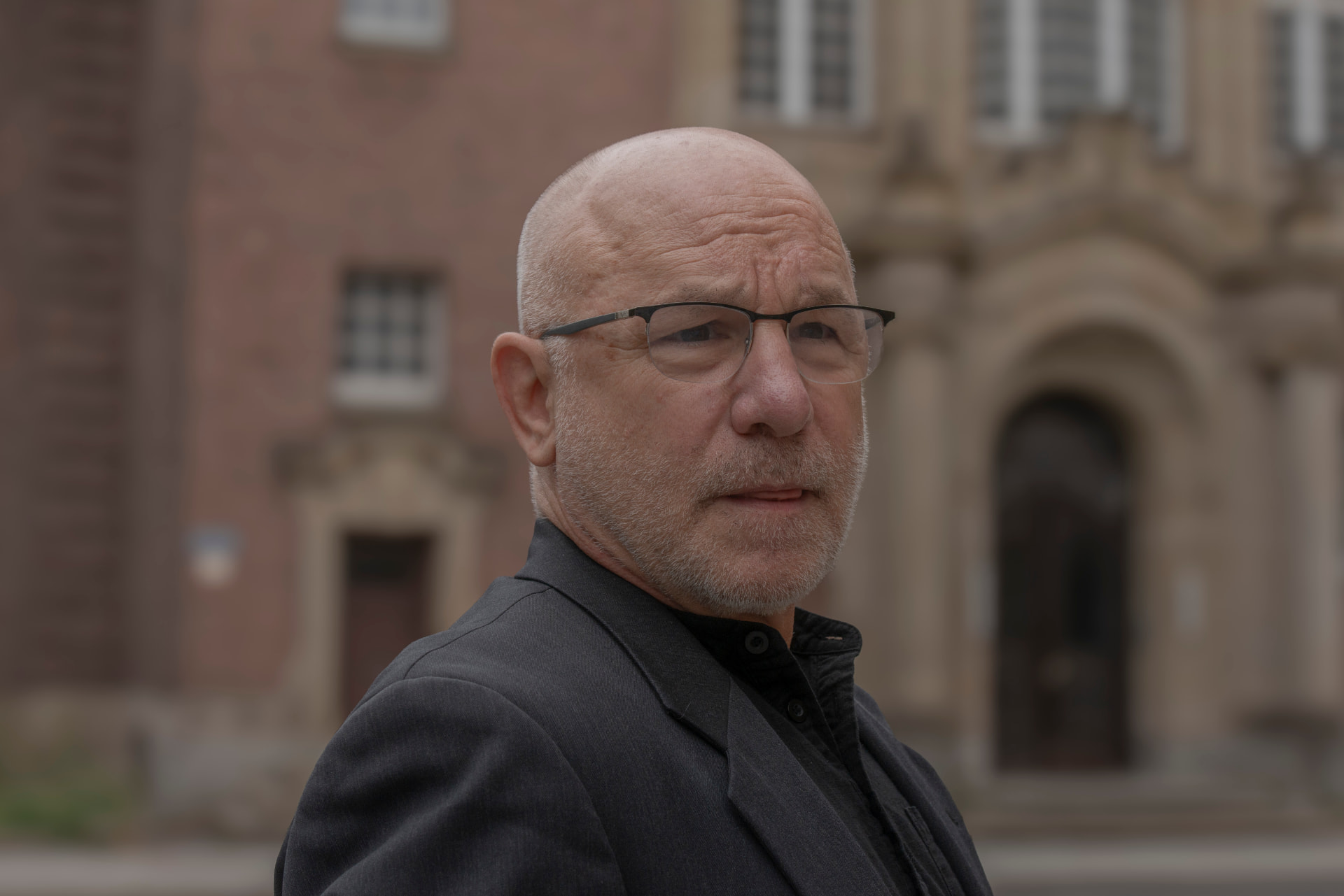 Dr. Donat Ebert mit Brille vor einer historischen Backsteinfassade